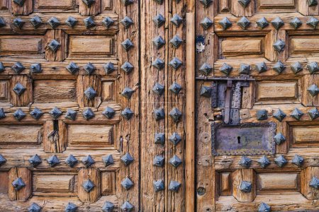 Téléchargez les photos : Vieille porte en bois de couleur marron avec clous rouillés et ferronnerie à l'extérieur d'une vieille église dans la ville de Lerma. - en image libre de droit