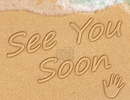 Foto de See You Soon Sign  on the sand on the beach with the sea washing up the shore - Imagen libre de derechos
