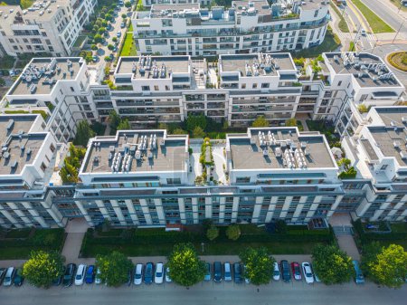 Téléchargez les photos : Vue aérienne du quartier des maisons résidentielles et du complexe d'immeubles d'appartements au coucher du soleil. Maisons serrées, allée entoure flyve arbre vert. Développement immobilier de banlieue - en image libre de droit