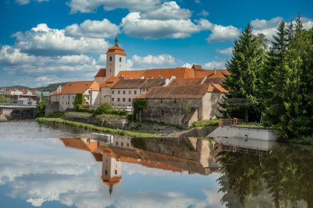Photo for Strakonice medieval castle reflecting off the Otava river with cloudy blue sky background - Royalty Free Image
