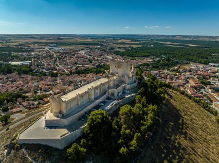 Aerial panorama view of Penafiel castle in Spain, with blue sky background, long walls enclose the top of the hill, three storey keep intersects in the middle a wall strengthened by circular towers