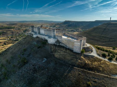Aerial view of restored Jadraque medieval hilltop castle in Spain in in the province of Guadalajara, CastillaLa Mancha, above the Henares river, with concentric towers blue sky with jet streams