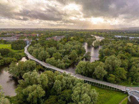 Foto de Vista panorámica aérea del Puente Viviente, curvo moderno paso peatonal sobre el río Shannon en la Universidad de Limerick con impresionante puesta de sol - Imagen libre de derechos