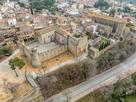 Aerial view of Calonge town and medieval castle with inner garrison courtyard surrounded by walls with crenallations and quare old tower, residential palace. Used as a venue for music festival in Catalonia Spain