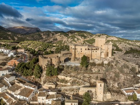 Luftaufnahme der Burg Velez Blanco auf einem Hügel und Stadt mit ein- oder zweistöckigen Häusern mit weiß getünchten Wänden und Ziegeldächern mit dramatischem bewölkten Himmel in Andalusien Spanien
