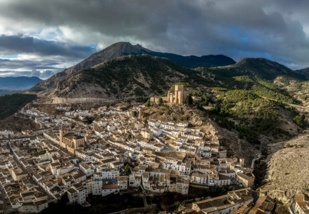 Luftaufnahme der Burg Velez Blanco auf einem Hügel und Stadt mit ein- oder zweistöckigen Häusern mit weiß getünchten Wänden und Ziegeldächern mit dramatischem bewölkten Himmel in Andalusien Spanien