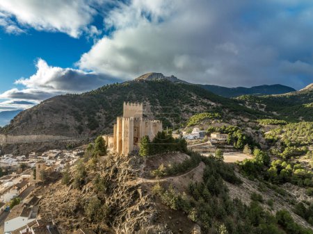 Photo for Aerial view of  Velez Blanco castle on a hilltop and town with one or two floor houses whitewashed walls and tiled roofs with dramatic cloudy sky in Andalusia Spain - Royalty Free Image