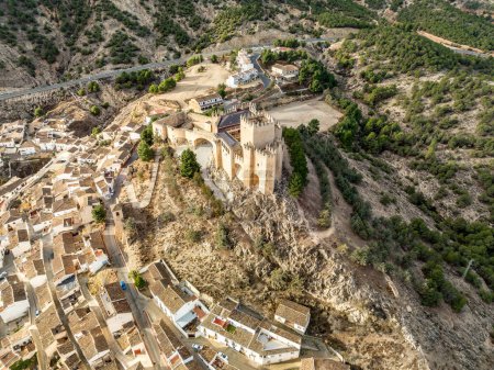 Aerial view of  Velez Blanco castle on a hilltop and town with one or two floor houses whitewashed walls and tiled roofs with dramatic cloudy sky in Andalusia Spain
