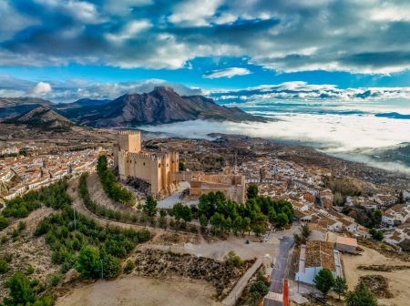 Vue aérienne du château de Velez Blanco sur une colline et une ville avec des maisons d'un ou deux étages murs blanchis à la chaux et des toits carrelés avec un ciel nuageux spectaculaire en Andalousie Espagne