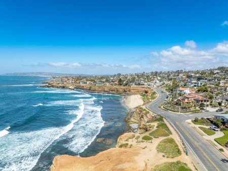 Aerial panorama of Sunset Beach in San Diego with ragged California ocean coastline, crushing waves, luxury single family homes and residences with pools