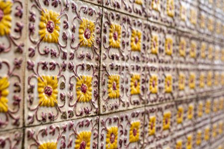 Téléchargez les photos : Fragment de mur de construction avec carreaux muraux en céramique jaune floral Azulejo Abstrait fond décoratif motif décoratif texturé. focus sélectif - en image libre de droit