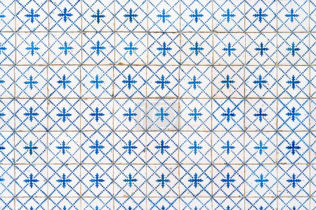 Fragment of building wall with white and blue ceramic wall tiles Azulejo Abstract decorative background textured ornate pattern. Traditional ornate Portuguese architecture 