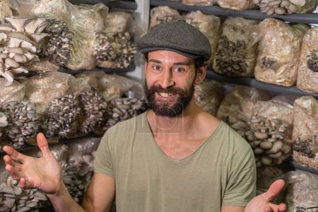 Photo for Portrait of excited owner of the oyster mushroom farm. young man smiling to camera against the background of roduction blocks of oyster mushrooms - Royalty Free Image