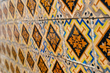 Téléchargez les photos : Fragment de vieux mur de bâtiment avec carreaux muraux en céramique jaune floral Azulejo Abstrait fond décoratif motif décoratif texturé. focus sélectif - en image libre de droit