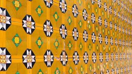 Téléchargez les photos : Fragment de mur de construction avec carreaux muraux en céramique jaune floral Azulejo Abstrait fond décoratif motif décoratif texturé. focus sélectif - en image libre de droit