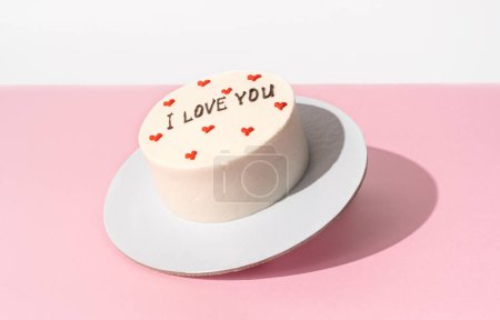 Kleine Bento-Torte schwebt auf dem minimalistischen rosa-weißen Hintergrund, harte Schatten