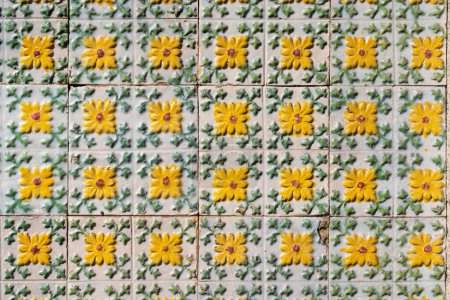 Téléchargez les photos : Fragment de mur de construction avec carreaux muraux en céramique jaune floral Azulejo Abstrait fond décoratif motif décoratif texturé. Architecture traditionnelle portugaise ornée - en image libre de droit