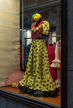 Téléchargez les photos : Belle robe de flamenco de couleur jaune espagnol dans la fenêtre d'un magasin de vêtements spécial. Vitrine - en image libre de droit