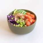 Hawaiian salmon poke bowl with sesame seeds, avocado, red cabbage and edamame on white background. Buddha bowl. Diet.