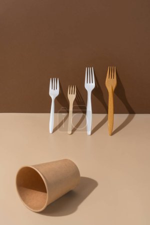 Foto de Ecológico diferentes tenedores y cupón vacío un fondo beige y marrón.. Biodegradable, alternativa componible al plástico. - Imagen libre de derechos
