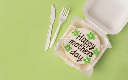 Happy mothers day mini cake on light green paper background with copy space