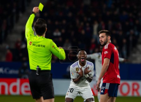Foto de Madrid, Spain- February 18, 2023: League match between Real Madrid and Osasuna in Pamplona. Vinicius Jr. receives a card from the referee. Football games. Real Madrid player. - Imagen libre de derechos