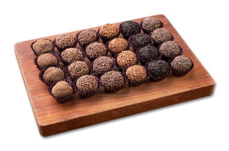 Typical brazilian brigadeiros, various flavors over wooden board isolated over white background.