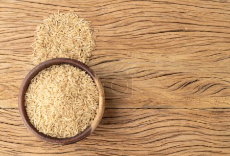 Photo for Raw brown rice in a bowl over wooden table with copy space. - Royalty Free Image