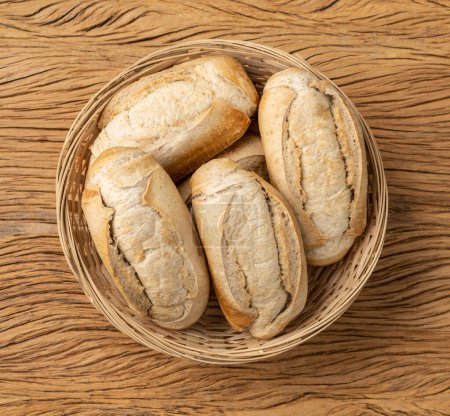 Téléchargez les photos : Pain français à grains entiers, pain salé ou pistolet dans un panier sur une table en bois. - en image libre de droit