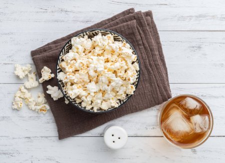 Téléchargez les photos : Popcorns sur un bol avec du sel et une table en bois de soda. - en image libre de droit