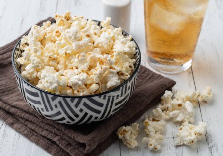 Téléchargez les photos : Popcorns sur un bol avec du sel et une table en bois de soda. - en image libre de droit