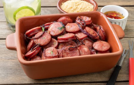 Téléchargez les photos : Grilled calabrese sausage portion with onion, farofa and caipirinha over wooden table. - en image libre de droit
