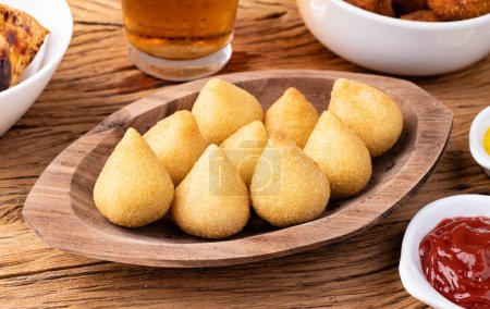 Photo for Typical brazilian snack coxinha on a plate with soda glass, ketchup and mustard. - Royalty Free Image