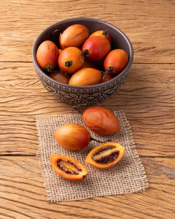 Tamarillos o tomates de árbol en un tazón sobre una mesa de madera.