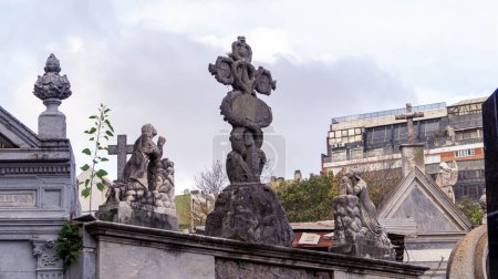 Photo for Stone sculptures of two womans praying to a cross shaped tree. Placed on top of a mausoleum at Recoleta cemetery - Royalty Free Image