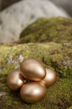 Foto de Four golden eggs on green mossy rock - Imagen libre de derechos