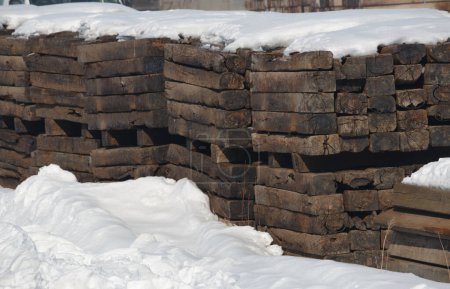 Téléchargez les photos : Empilements de vieilles traverses de chemin de fer vintage en bois entourées de neige - en image libre de droit