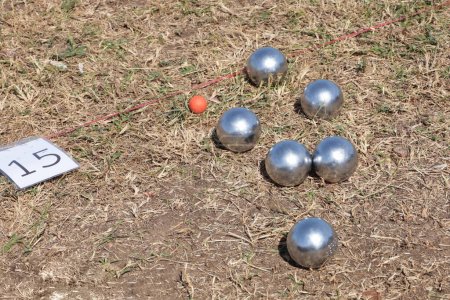 Boules in the lawn. Close-up of steel balls of traditional French game of petanque in an outdoor racetrack during holidays with copy space and focus.