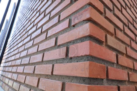 Photo for Red brick wall corner. Closeup of red brick and orange brick border with concrete wall of modern building or house with copy space with selective focus. - Royalty Free Image