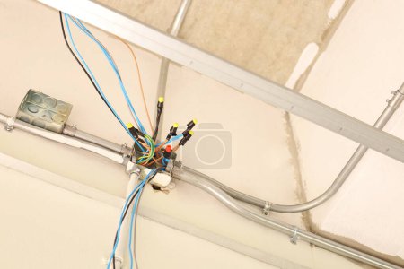 Photo for Wire Nut connects electrical wires in a junction box. Plastic insulating clamps encase twisted wire connections in metal distribution boxes with conduit pipes on concrete walls. Selective focus - Royalty Free Image