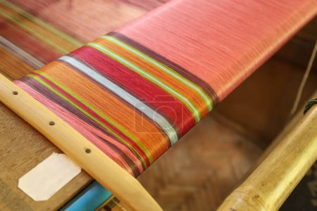 Hilos de seda tailandeses en un telar. Primer plano de hilos de seda de colores en telares locales utilizados para tejer prendas artísticas en la Tailandia rural con enfoque selectivo.