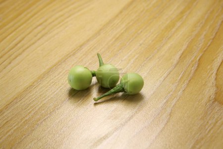 Berenjena verde pequeña berenjena salvaje sobre fondo de madera. Solanum paniculatum. Cereza de Turquía.