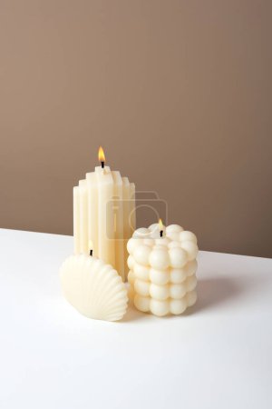 Photo for Olive wax burning candle on a duotone brown and white background. Sustainability vegan candle, natural materials. Minimalistic, vertical modern photo. Isometric diagonal projection. Copy space. - Royalty Free Image