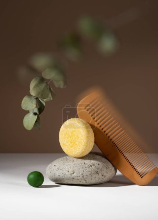 Photo for Abstract still life composition of a solid shampoo bar with surreal effect. Shampoo bar and a wooden comb balancing on a brown background. Plastic free, zero waste, low water ingredients. - Royalty Free Image