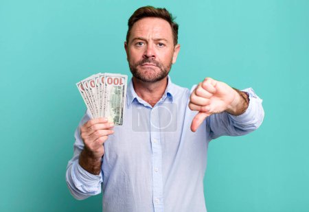 Photo for Middle age man feeling cross,showing thumbs down. dollar banknotes concept - Royalty Free Image