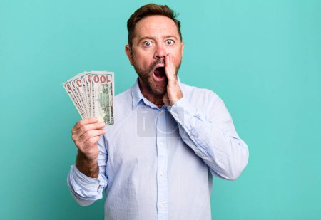 Foto de Middle age man feeling shocked and scared. dollar banknotes concept - Imagen libre de derechos