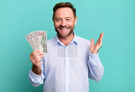 Foto de Middle age man feeling happy, surprised realizing a solution or idea. dollar banknotes concept - Imagen libre de derechos