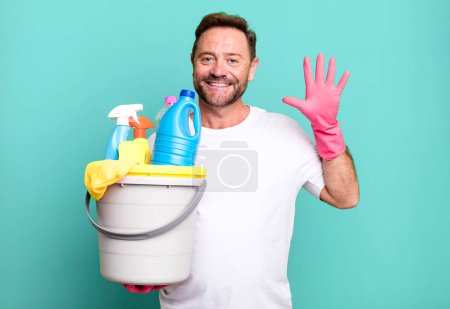 Photo for Middle age man smiling and looking friendly, showing number five. housekeeper with clean products - Royalty Free Image
