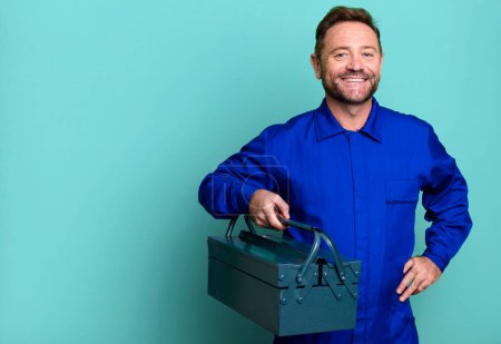 Photo for Middle age man smiling happily with a hand on hip and confident. plumber with a toolbox concept - Royalty Free Image