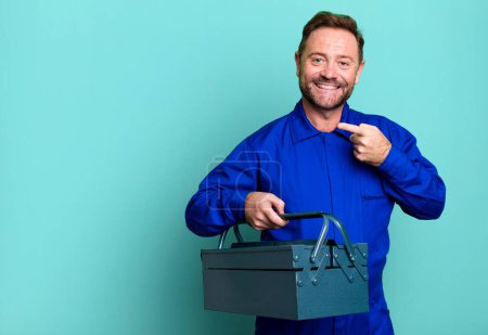Photo for Middle age man smiling cheerfully, feeling happy and pointing to the side. plumber with a toolbox concept - Royalty Free Image